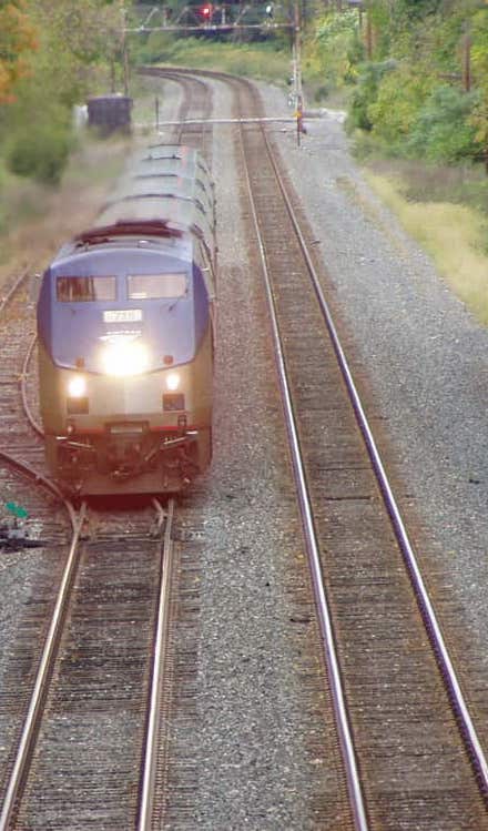 passenger train on tracks going through wooded area