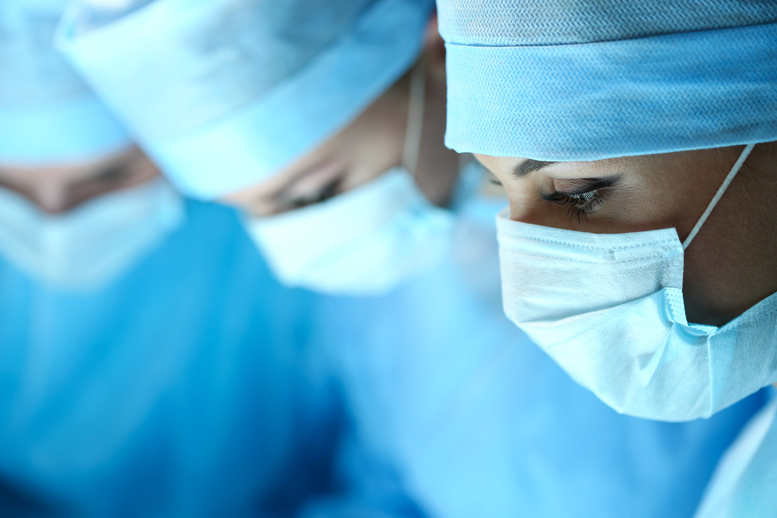 Three surgeons at work operating in surgical theatre